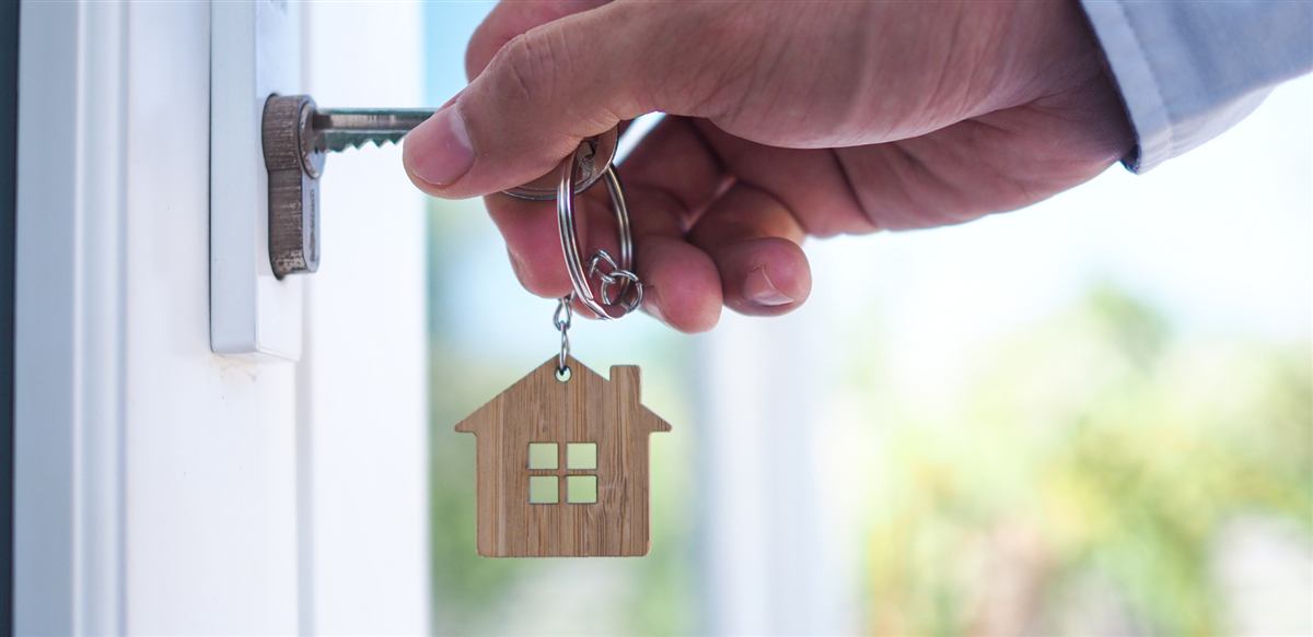 A hand turning a key in the front door of a home