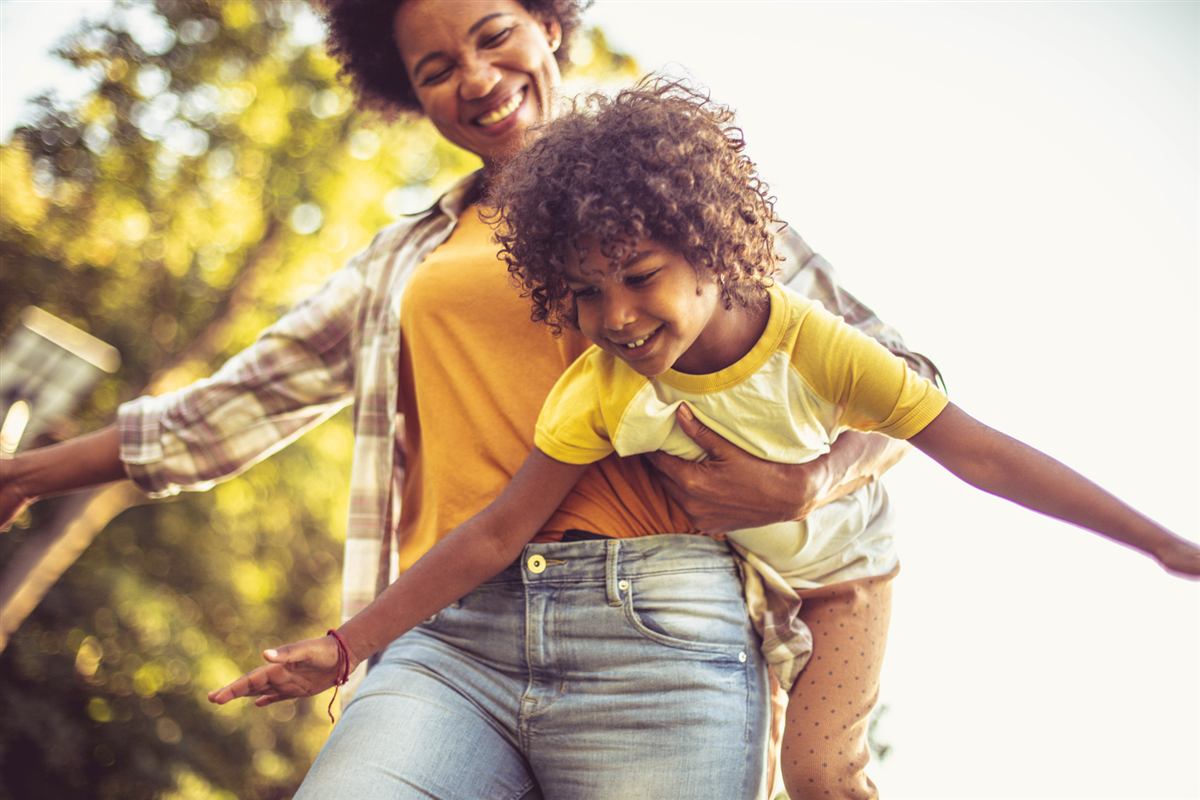 A mother laughing as she plays with her daughter in a park
